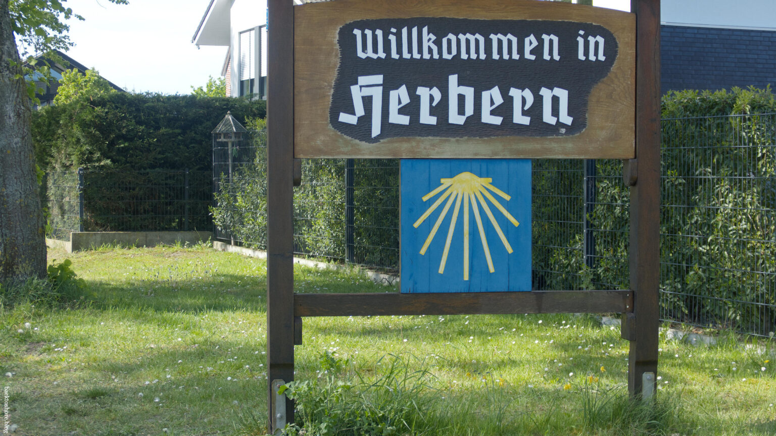 Welcome to Herbern sign with a large scallop waymarker