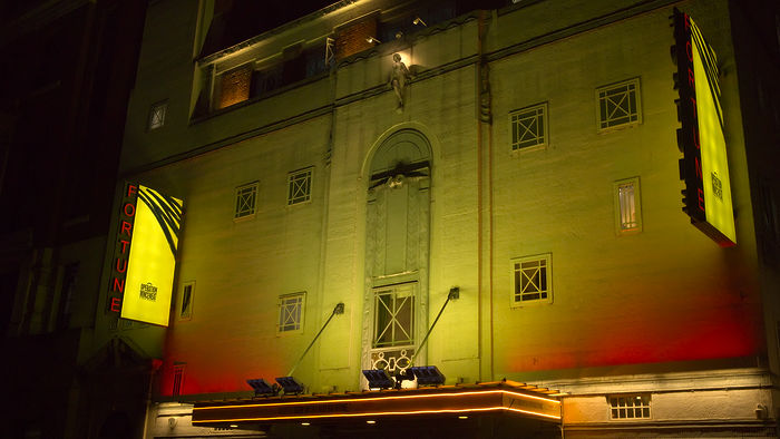 Fortune Theatre with the Operation Mincemeat marquee, basked in yellow light at night