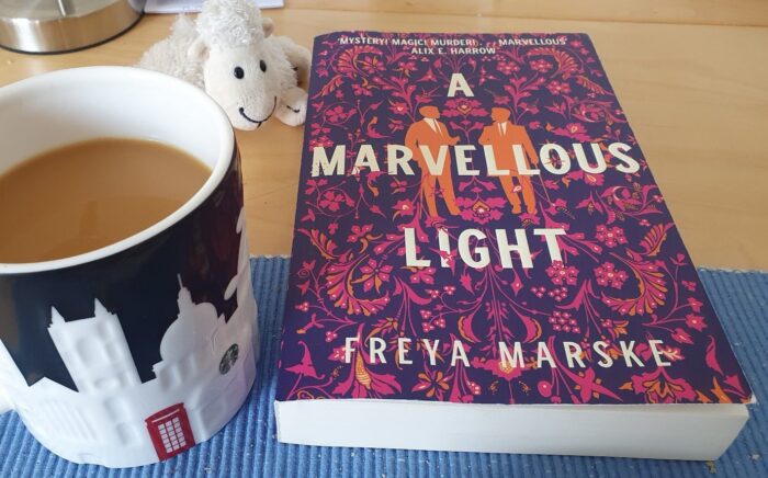 Large mug with a London skyline, filled with coffee, next to the novel "A Marvellous Light"