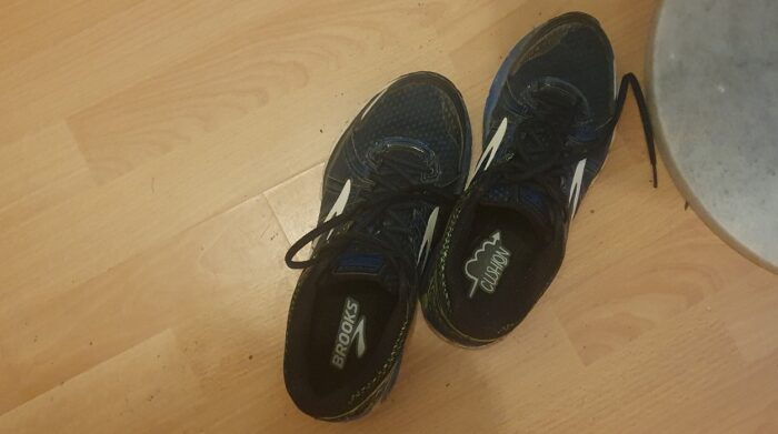 A pair of dark blue running shoes on a wooden floor
