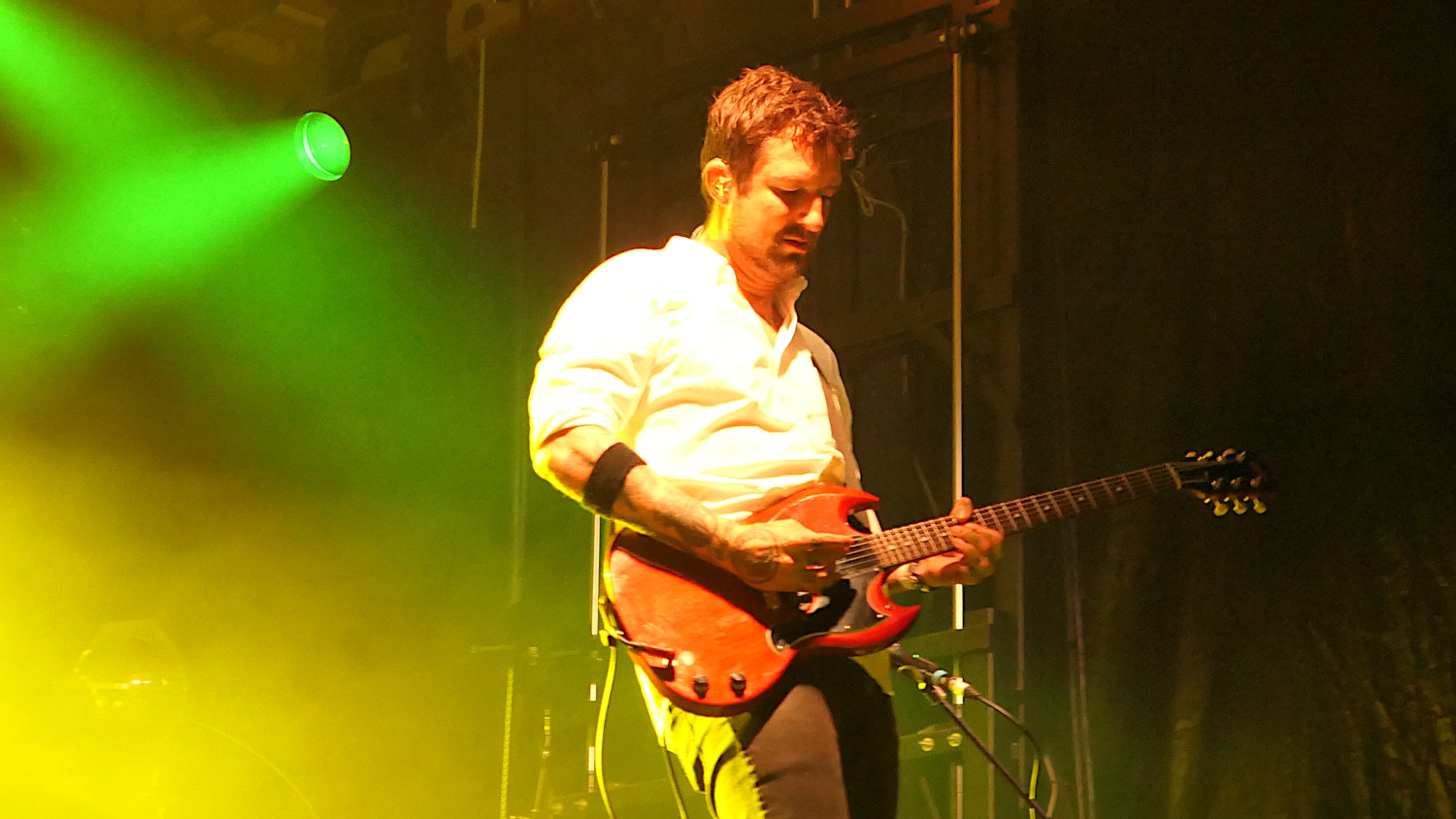 Frank Turner playing a red/brown electric guitar. Green/yellow lighting in the background