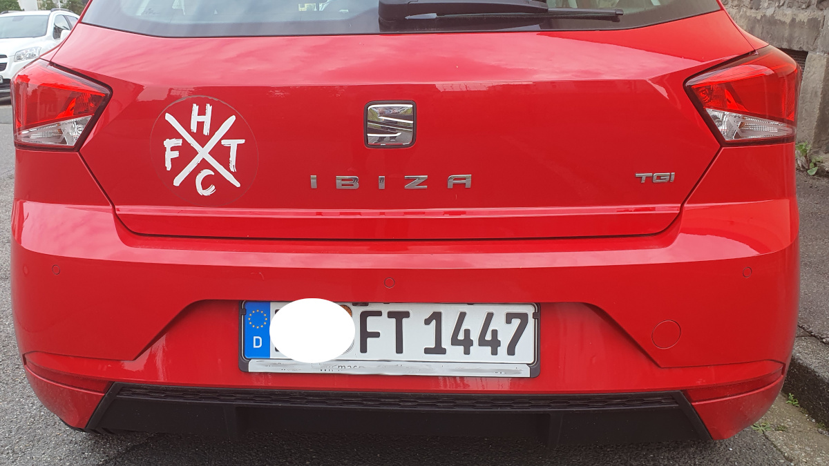 Photo of the rear of a read Seat Ibiza, with a FTHC sticker on the rear and a FT - 1447 licenceplate