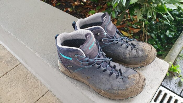 Blue hiking boots with a lot of mud on them
