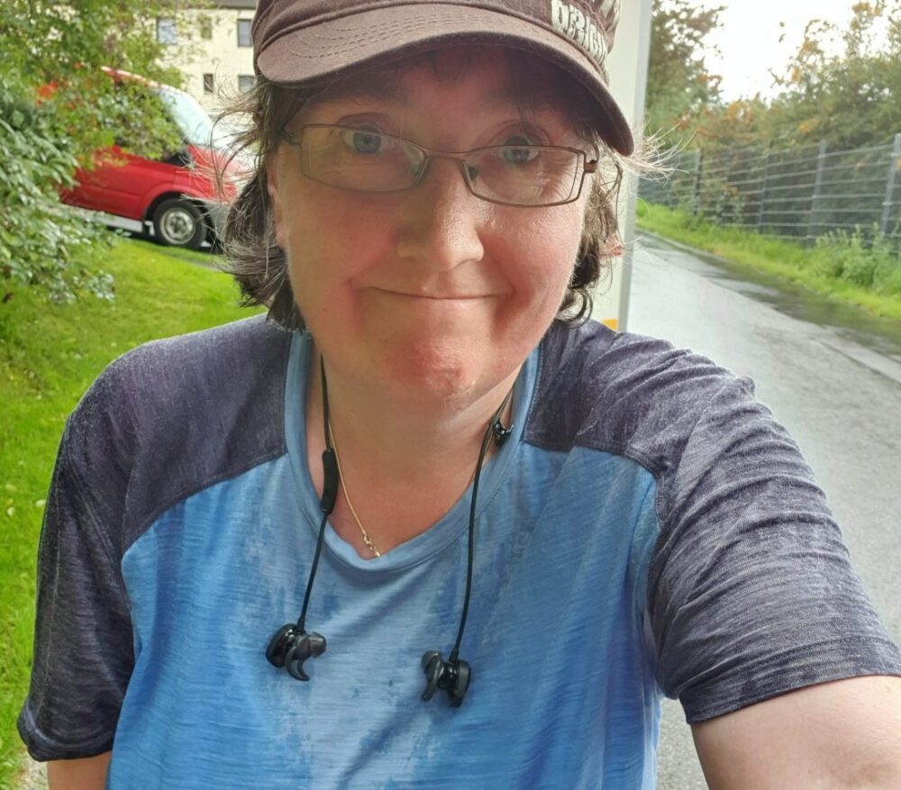 Photo of me with a hat on, wearing a light blue t-shirt. The shirt is soaked from rain