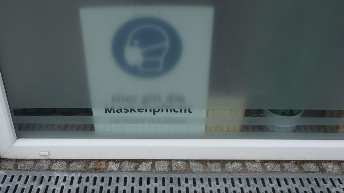 Photo of a "Mask Mandatory" sign behind a window