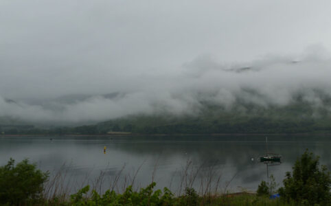 Photo of a loch in Scotland with low hanging clouds over the water.