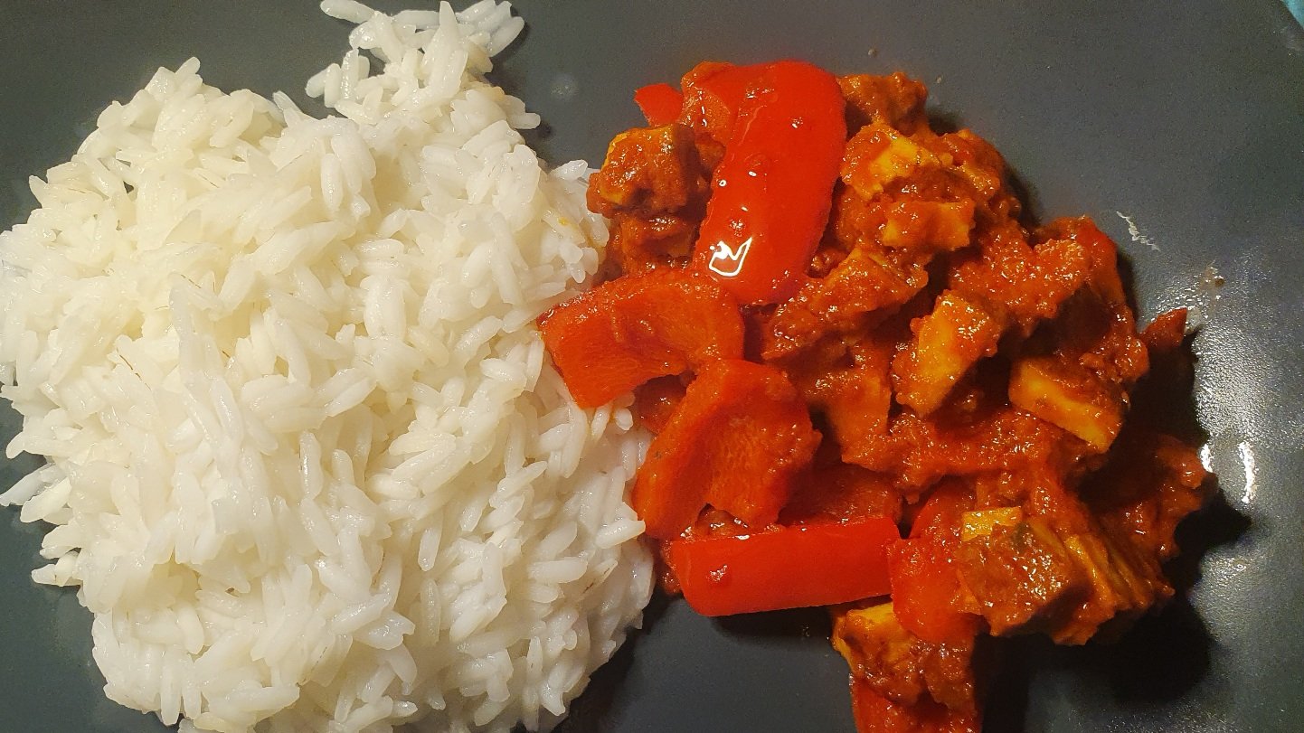 Photo of white rice and a tofu, pepper, tomato dish on a grey plate