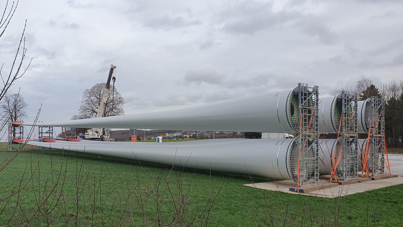Photo of six 80 m long wind turbine blades stored on a field