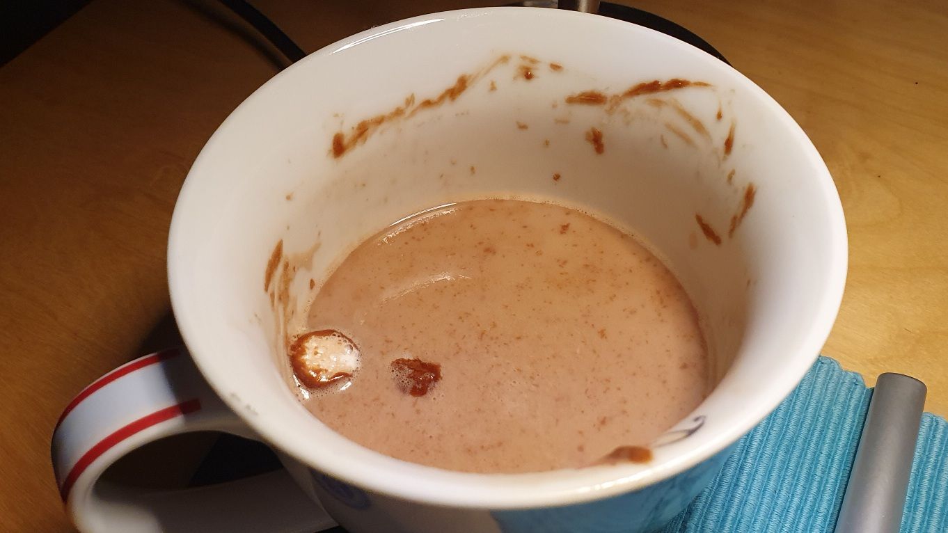 Photo of a mug half filled with hot chocolate and small marshmallow balls