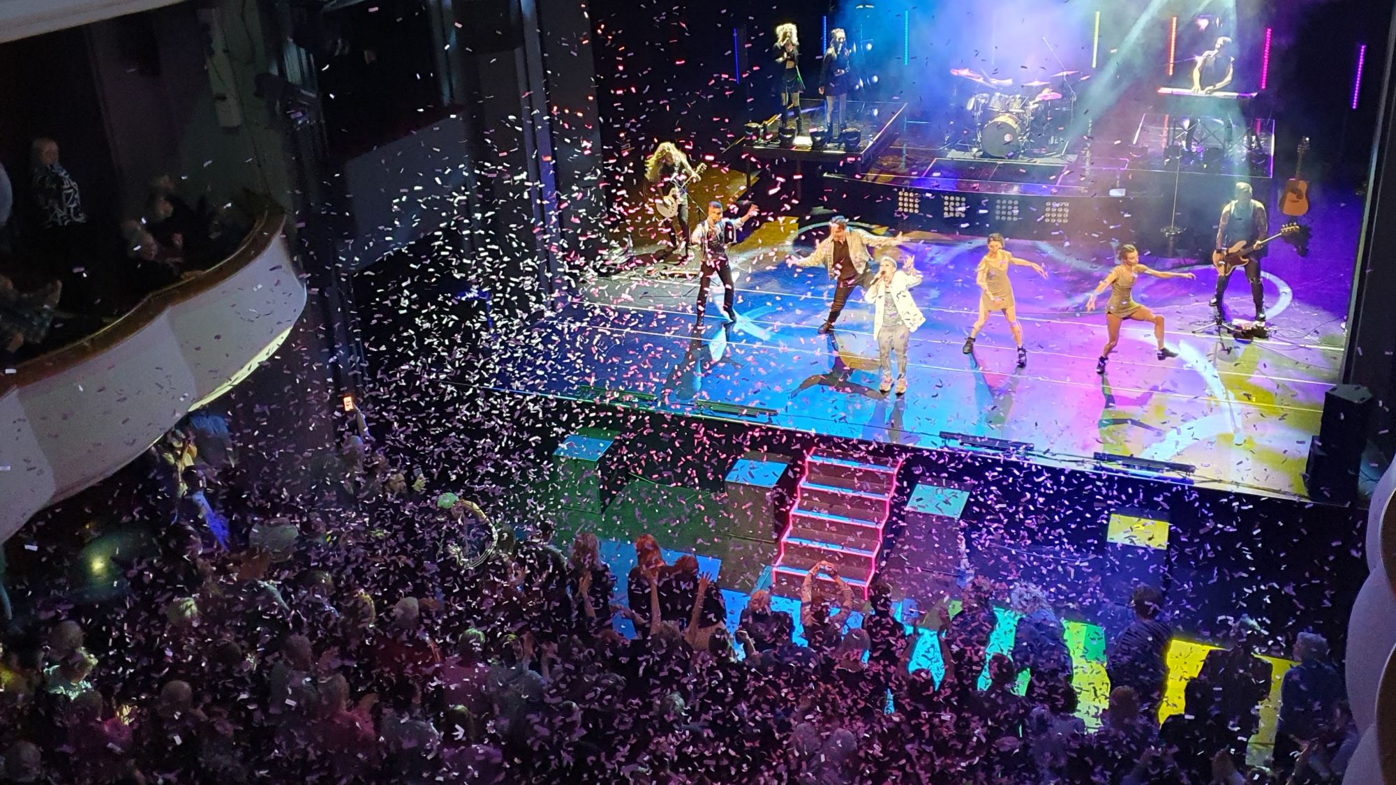 View from the balcony onto a theatre stage, P!NK tribute show, dancers and band, pink confetti in the air