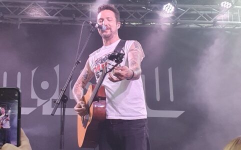 Frank Turner on stage, changing the tuning of his guitar