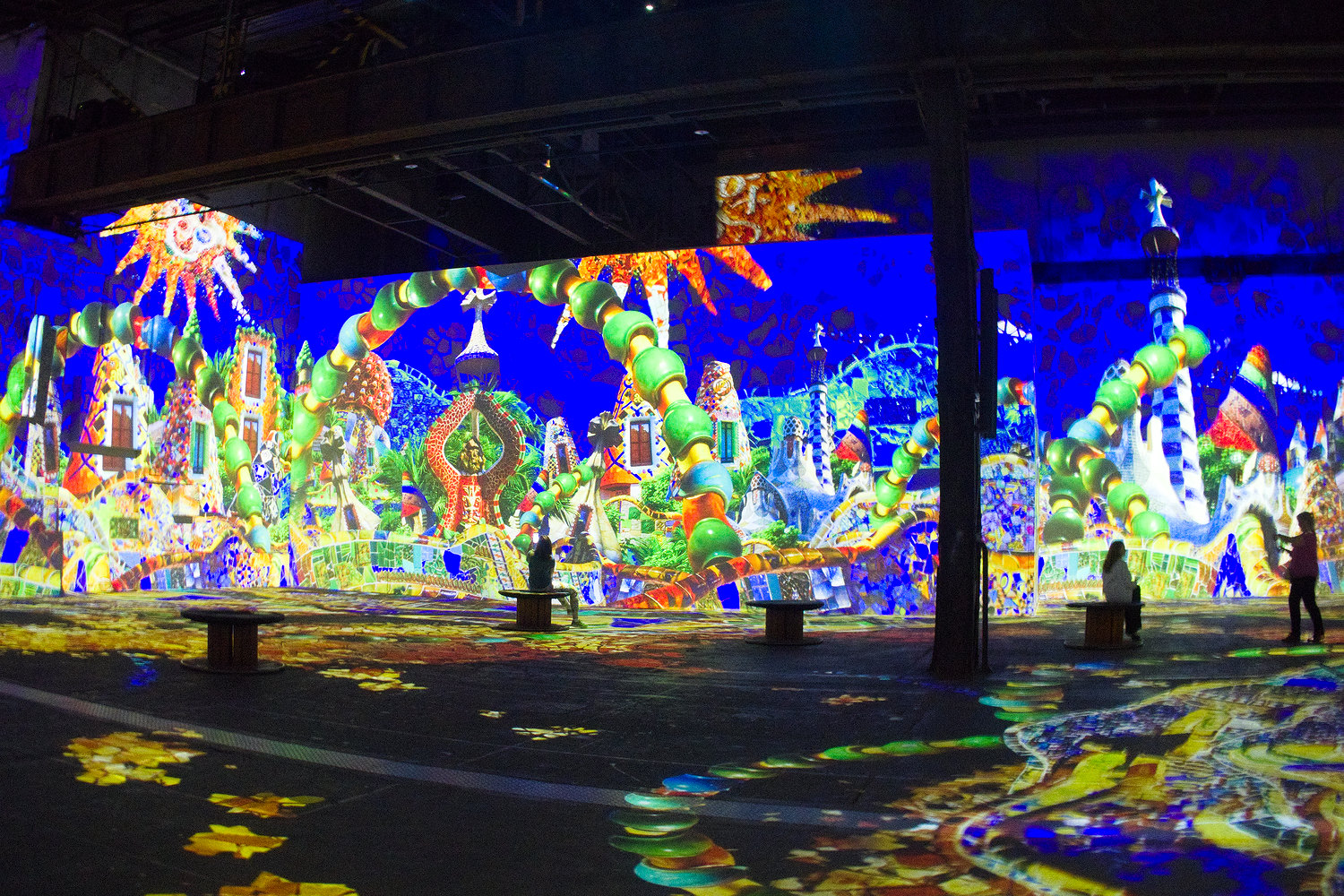 Inside a spacious former industrial space, colourful Gaudi art images projected on the walls