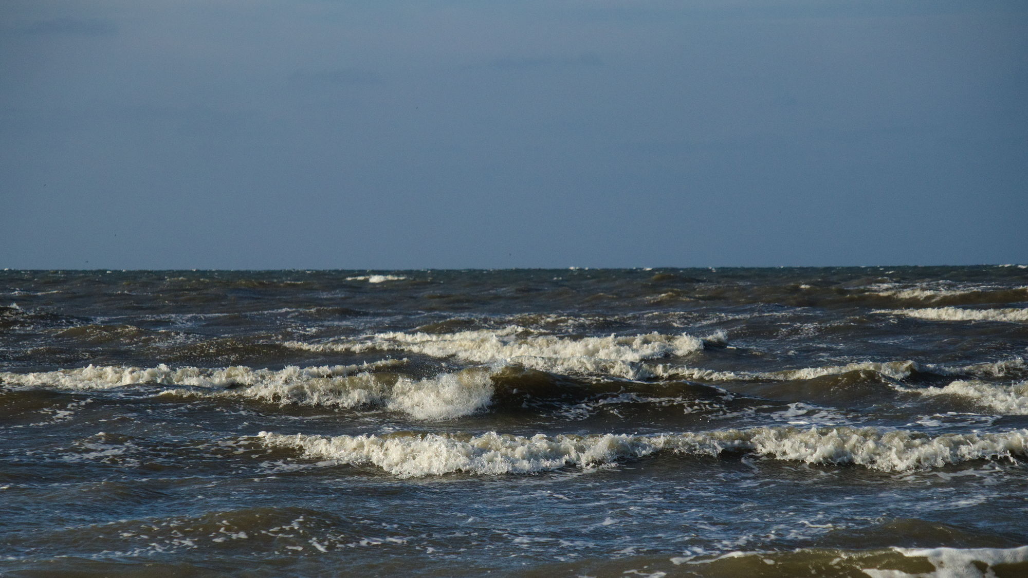 Sligtly choppy sea in the lower half, clear blue sky above