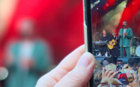 Photo of a phone camera taking a photo of Sasha on stage