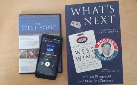 Photo of a DVD, phone with the podcast and the book of the West Wing