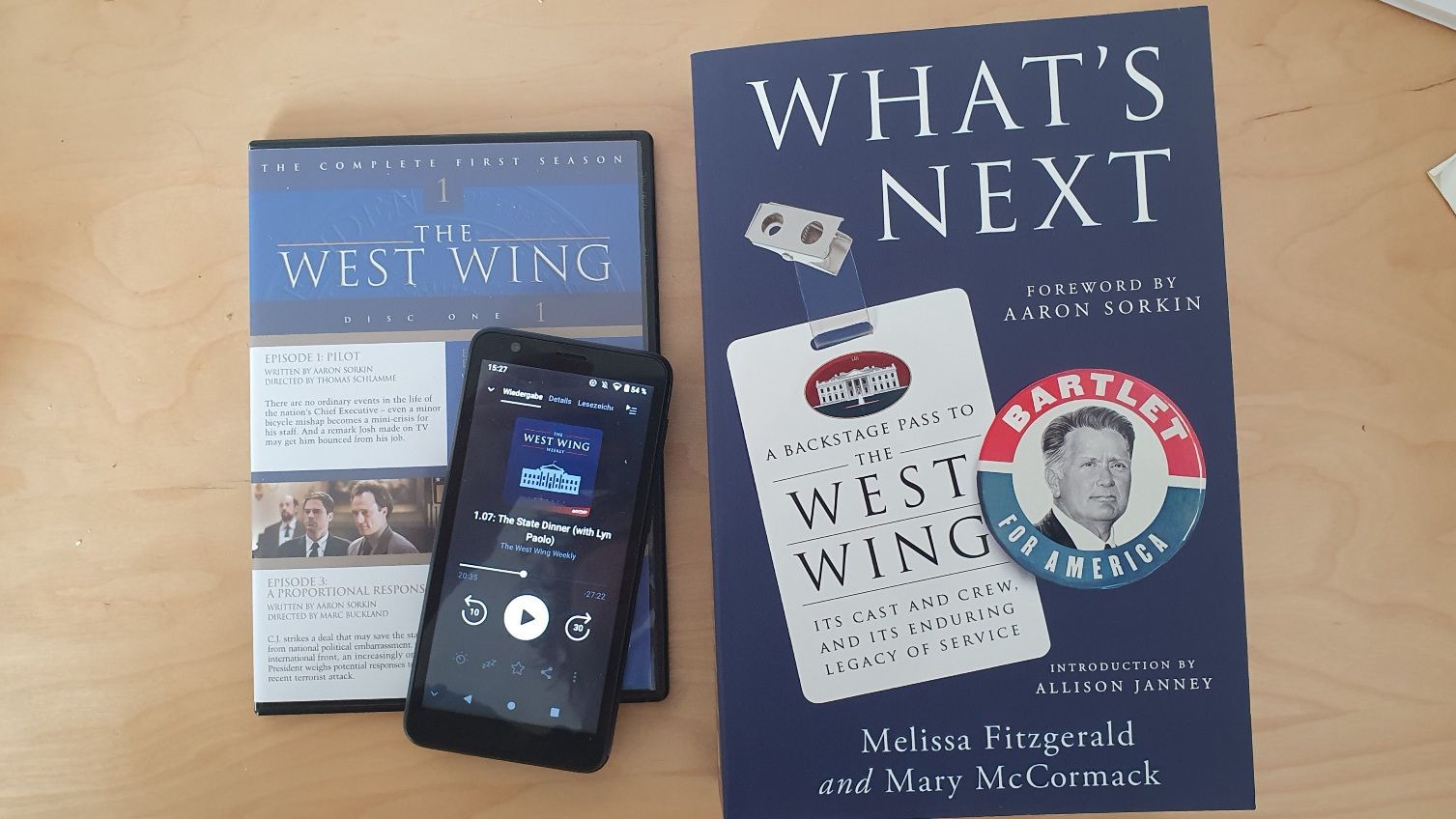 Photo of a DVD, phone with the podcast and the book of the West Wing