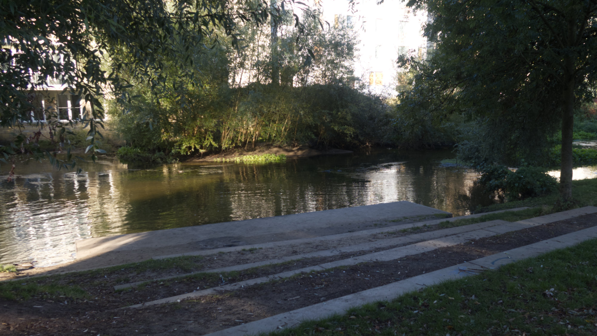 large steps leading down to a small river, lots of green around