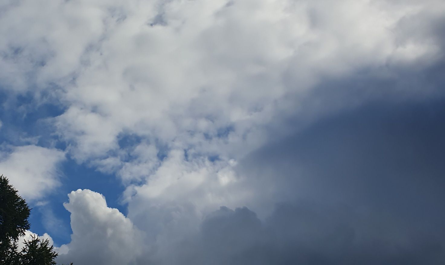 A bit of blue sky, lots of white clouds, a dark cloud in the lower right corner