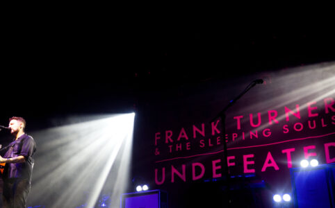 Frank Turner solo with a pink light backdrop