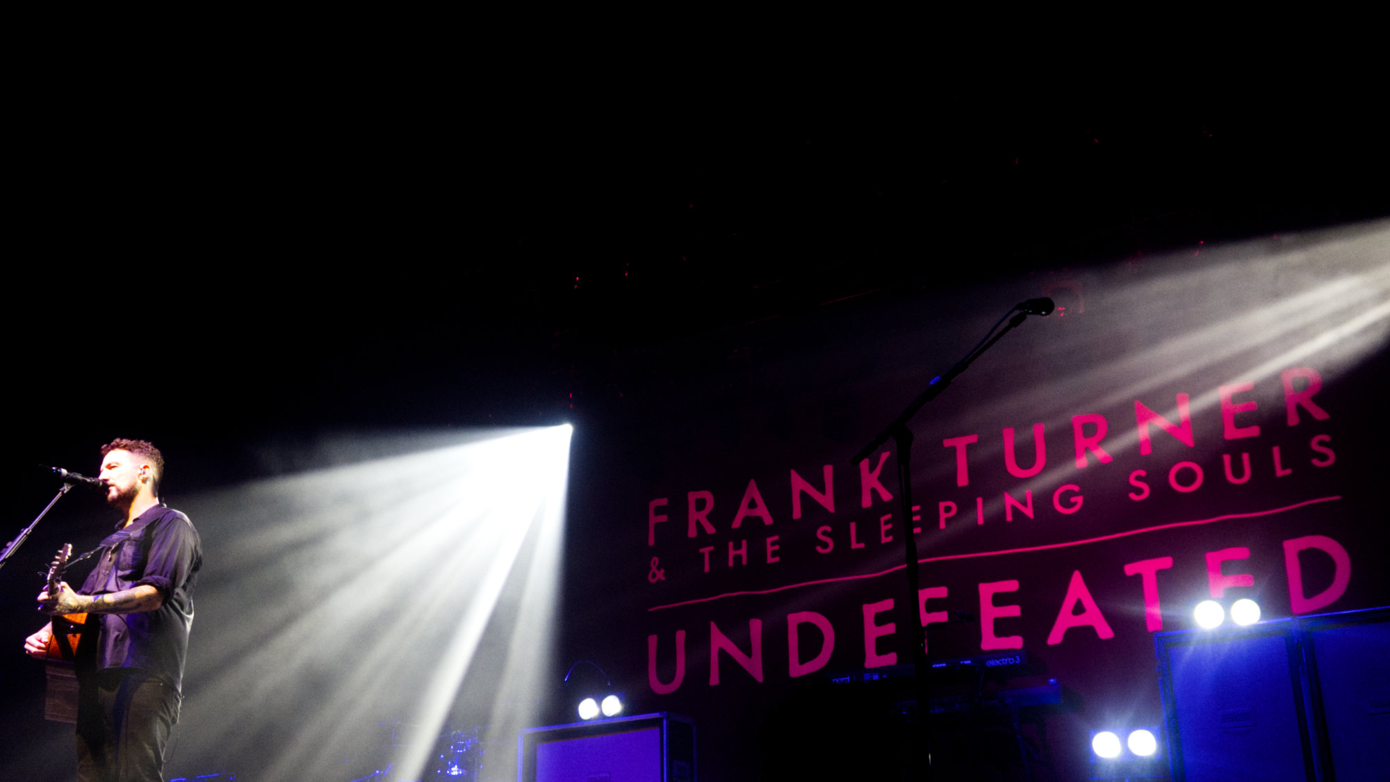 Frank Turner solo with a pink light backdrop