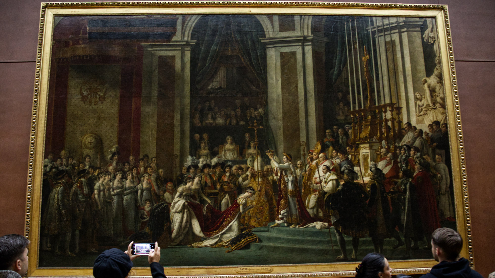 Painting "The Coronation of Napoleon" with people looking at in the Louvre