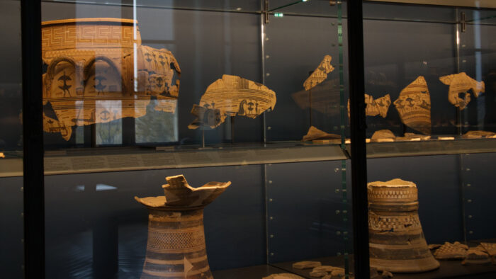 Greek pottery pieces behind glass