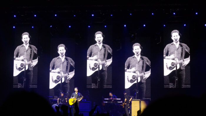 Frank Turner on stage and five fold on the screen behind him