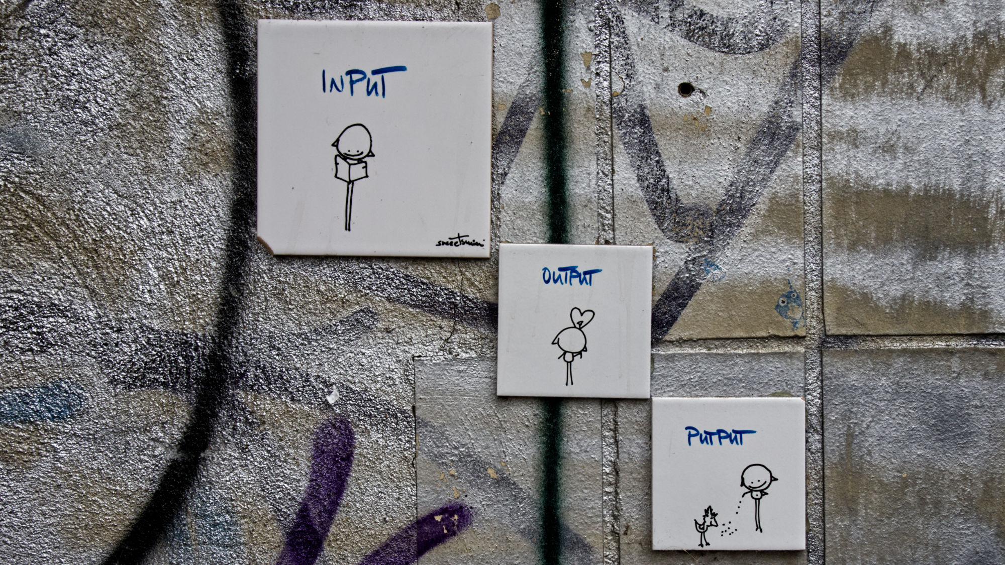 Small artwork on three tiles. First Input with a reading person. Output with a speaking person. Putput with a person feeding a chicken