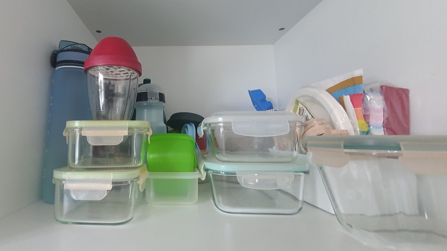 Glass storage containers, water bottles, napkins in a cupboard