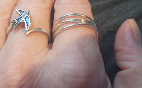 Blues swallow ring in middle finger, stacking waves ring on pointer