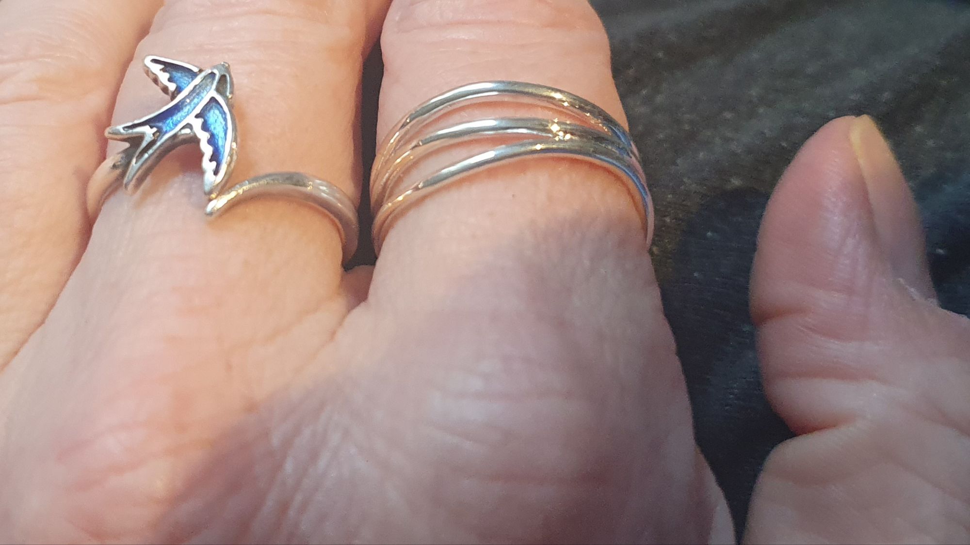 Blues swallow ring in middle finger, stacking waves ring on pointer 